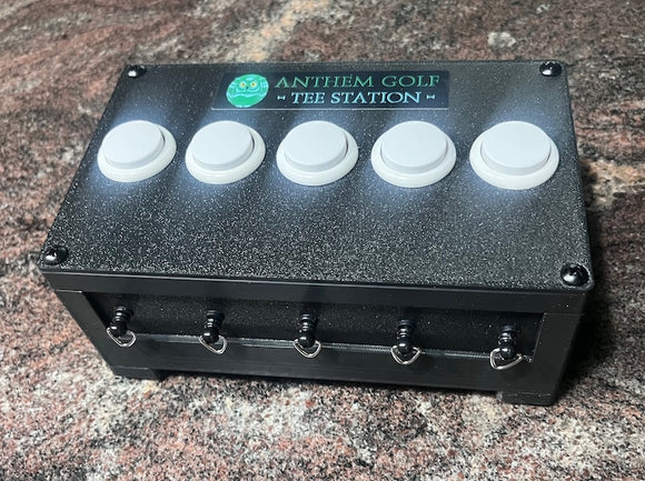A black control box with five white push buttons on top and five silver terminal screws on the front, branded 'ANTHEM GOLF TEE STATION'.