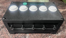 A black golf club bag with five white buttons on top and five metal loops on the front, branded 'Anthem Golf Tee Station'.