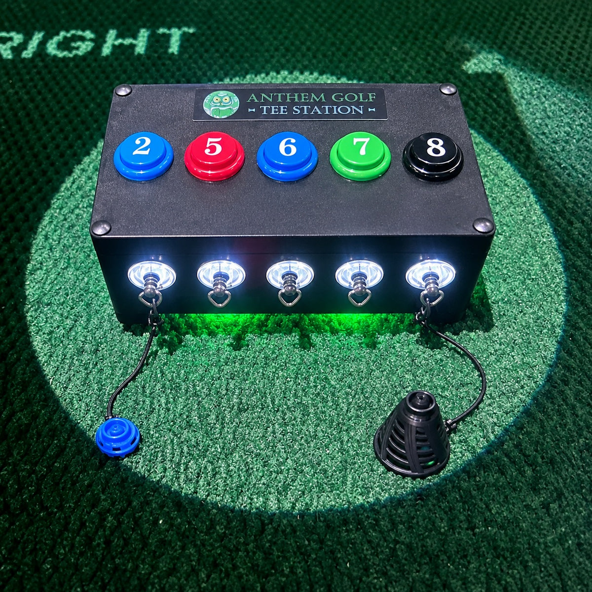 Lighted Anthem Golf Tee Station Birtee Edition on a simulator hitting mat, numbered buttons blue 2, red 5, blue 6, green 7, black 8, with the blue size 2 and black size 8 Birtees on their tethers