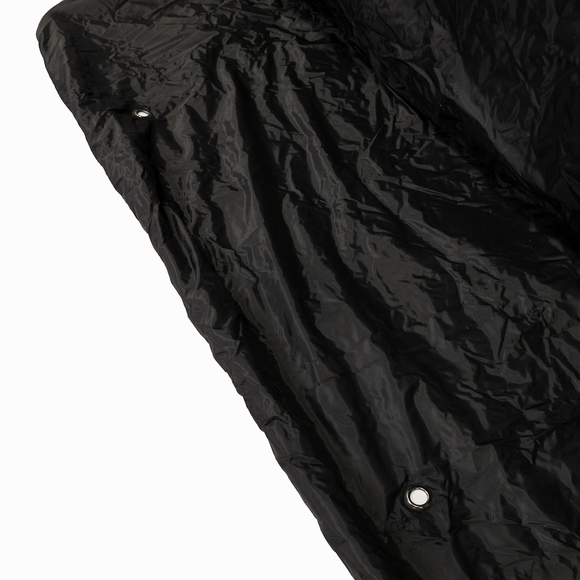Close-up of a crumpled black fabric with a metal grommet on the left side.