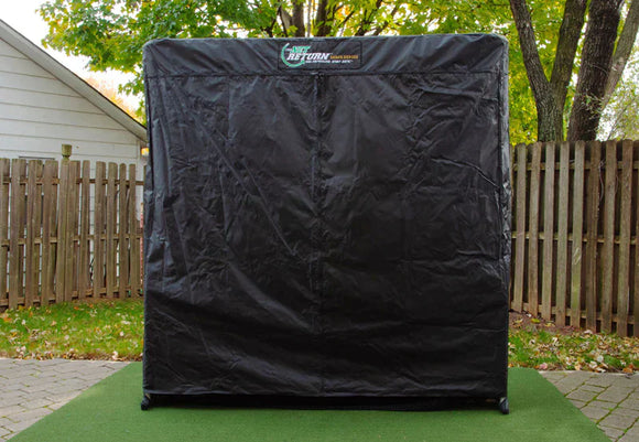 A black golf net setup outdoors on a patio, surrounded by a wooden fence and trees with green leaves.