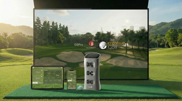 Golf simulator setup with screen, devices, and ball on a grassy area.