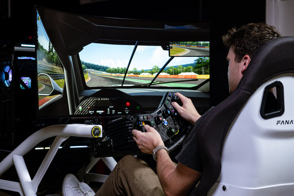 Person using a racing simulator with a detailed dashboard and steering wheel.