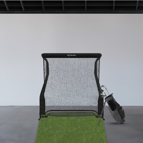 Golf hitting net set up indoors on a patch of artificial grass next to a golf bag.