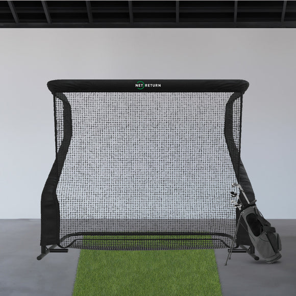 A golf practice net is set up indoors with a green mat and a golf bag nearby.
