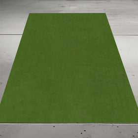 A rectangular patch of green artificial grass is laid on a gray concrete floor.