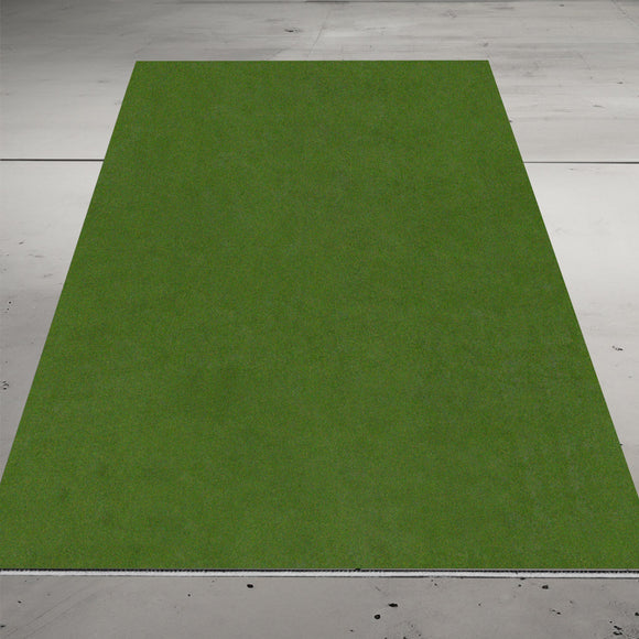 A rectangular patch of artificial grass lies on a concrete floor.