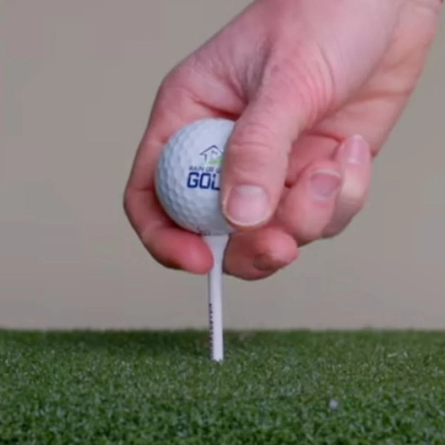 Golfer pushing a real tee into SwingTurf turf