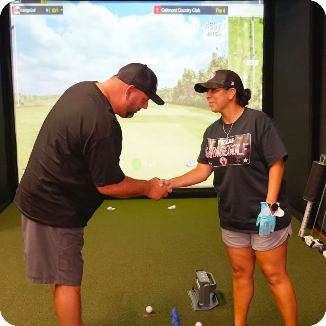 Garage Golf owner Roland and his wife shake hands while standing in a golf simulator